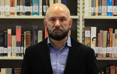 Foto de Juan Carlos Córdoba Laguna Juan Carlos Córdoba Laguna posando de frente con una estantería de libros en la parte de atrás